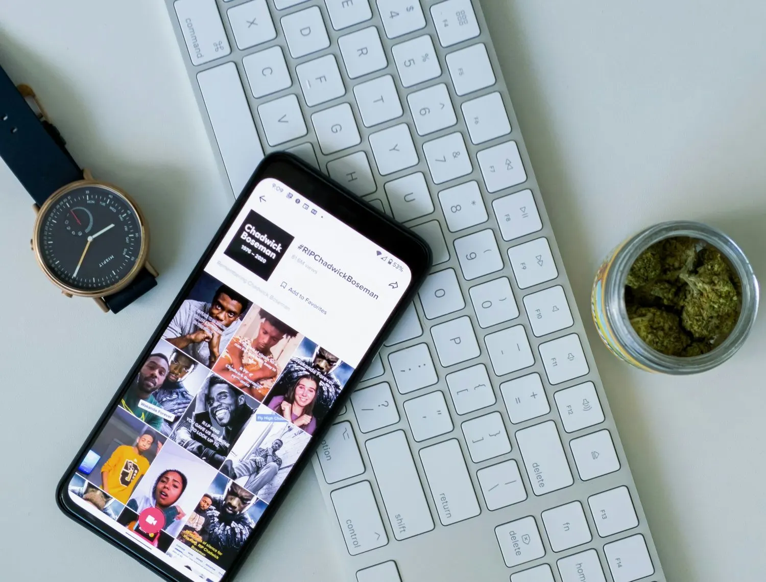 Smartphone displaying a social media app beside a keyboard and watch.