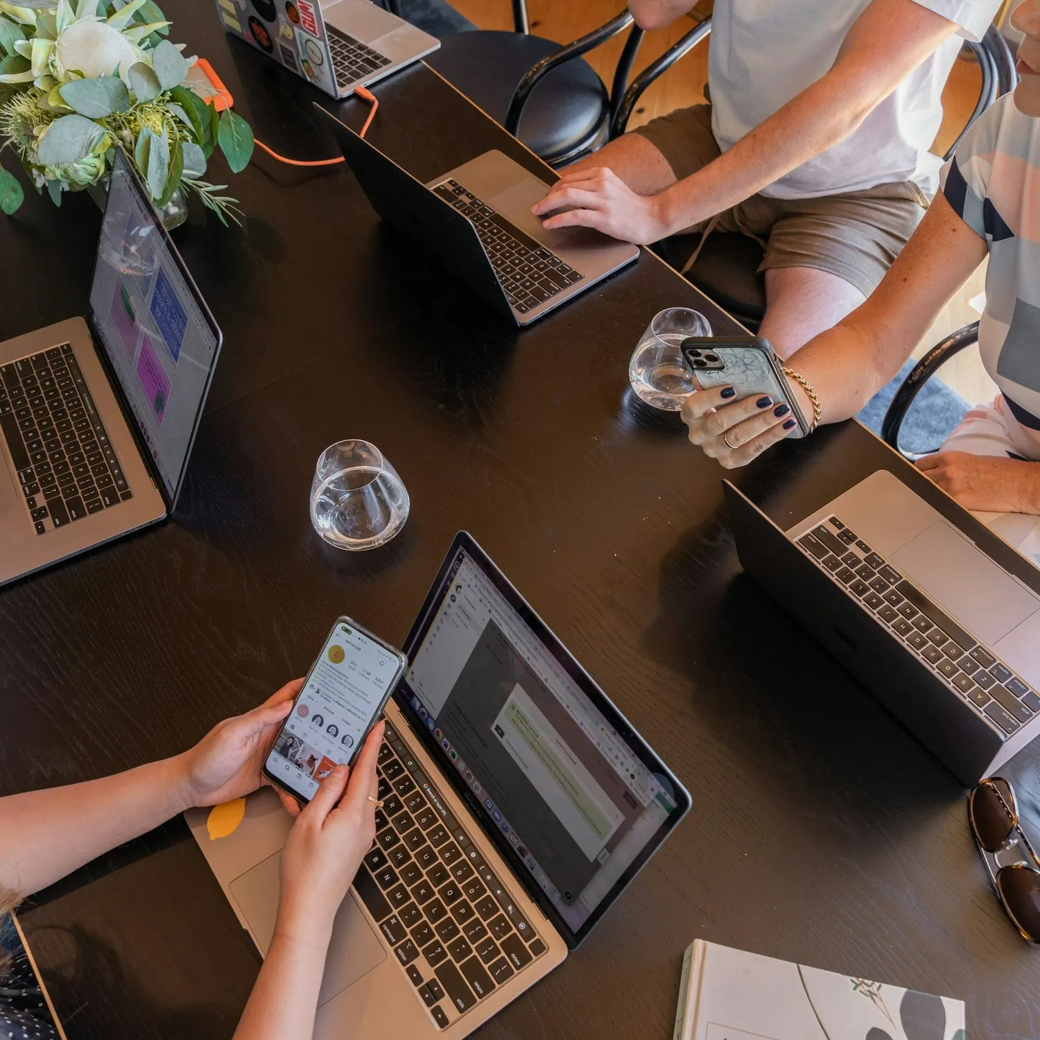 Team collaborating with laptops and smartphones around a meeting table.