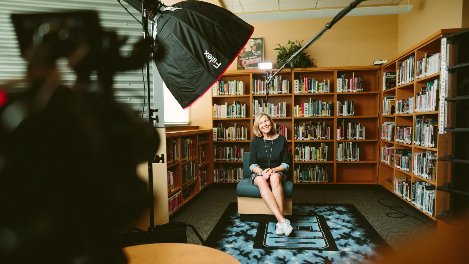 Woman being filmed in a library with professional video equipment.
