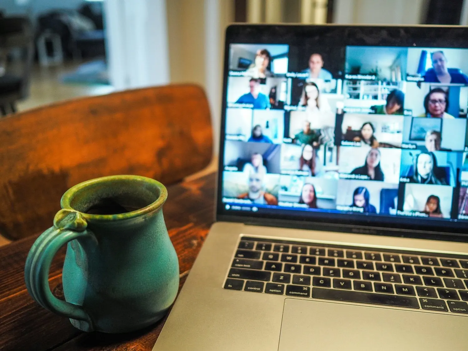 Laptop displaying a virtual video meeting beside a coffee mug.