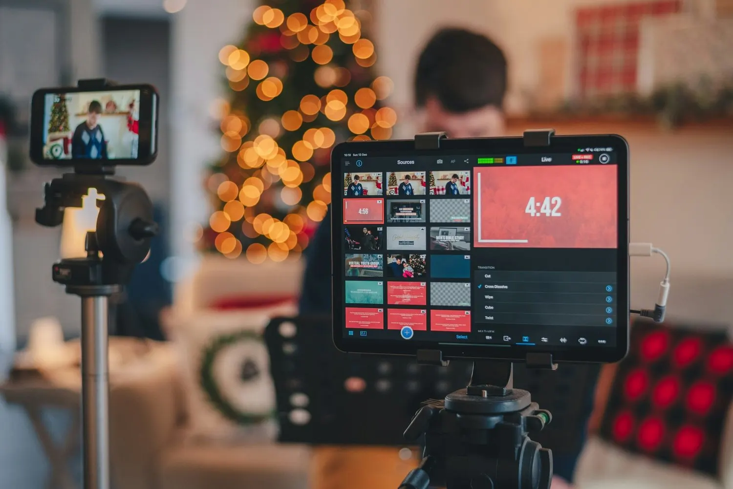 Tablet and smartphone set up for a live video broadcast near a Christmas tree.