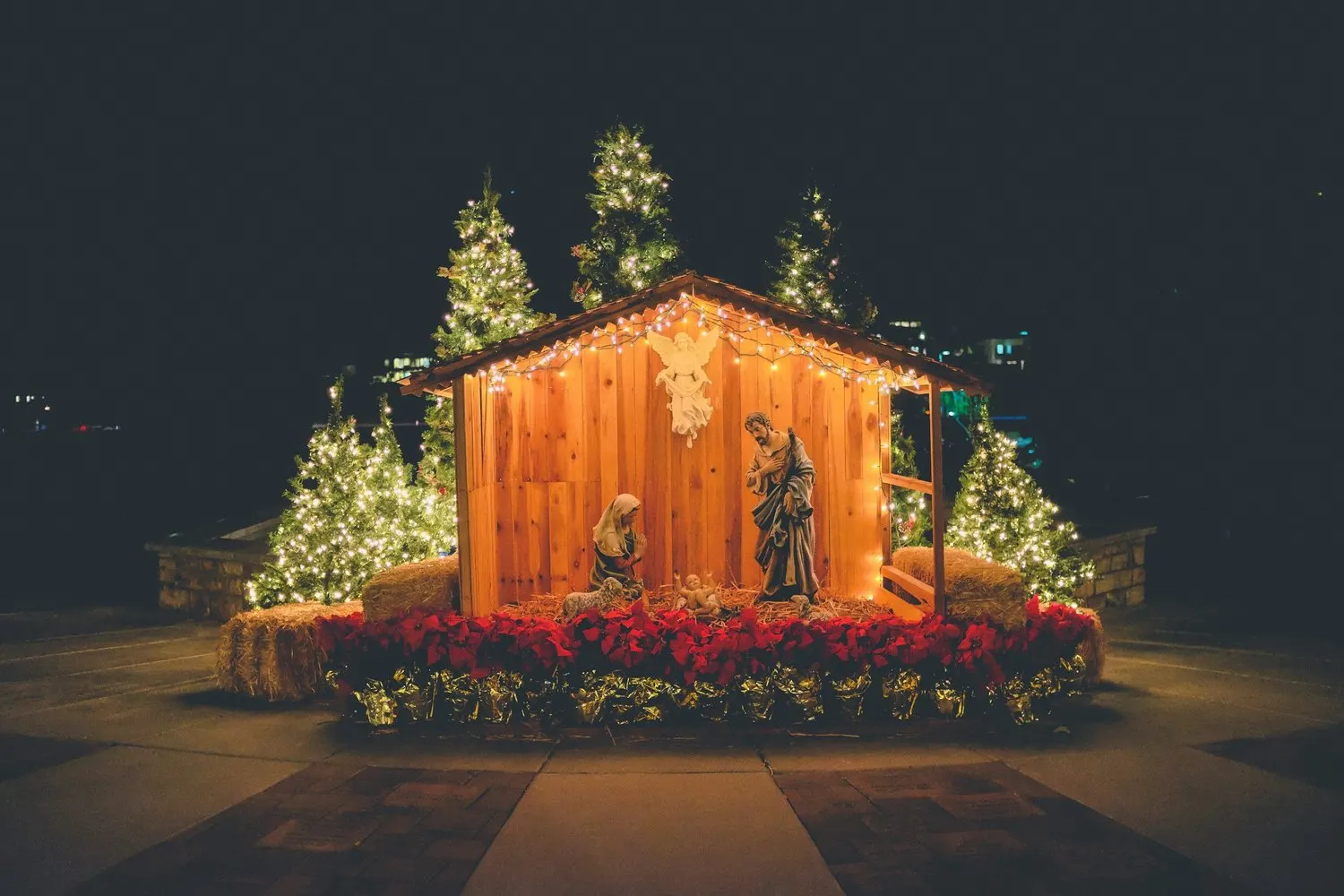 Nativity scene illuminated with Christmas lights at night.